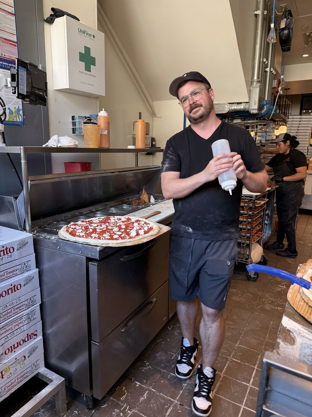 Andy standing proudly next to a fresh pizza he just made