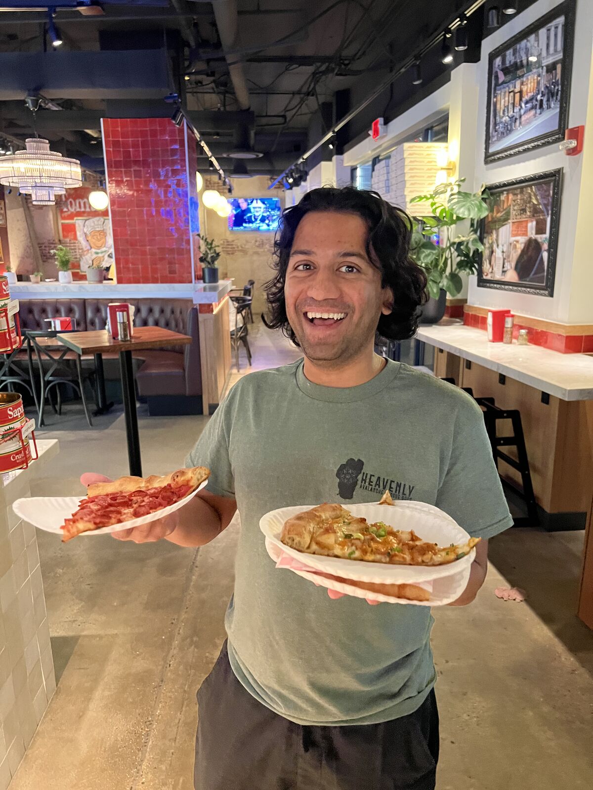 Sameer grinning with two slices of Andy's pizza
